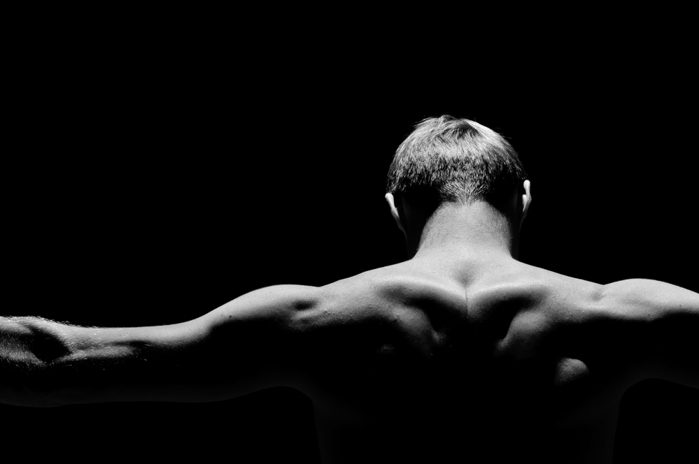 Back of the strong man on a black background